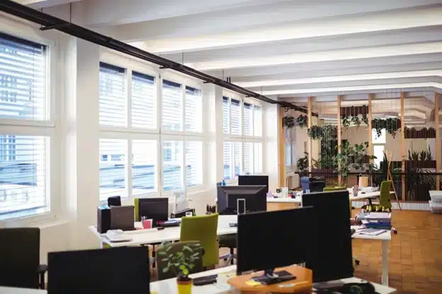 Modern office interior with clustered desks and a hanging living wall of plants.