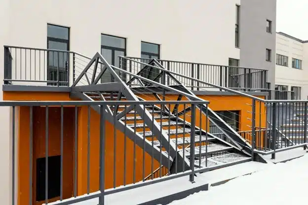 Exterior of two buildings connected by an industrial style staircase. 