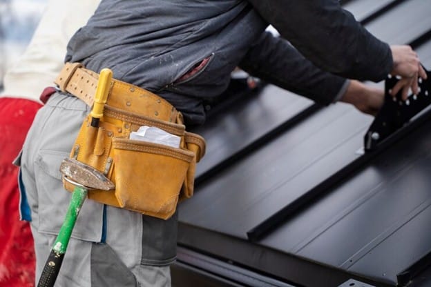 A handman bending over a metal roof.
