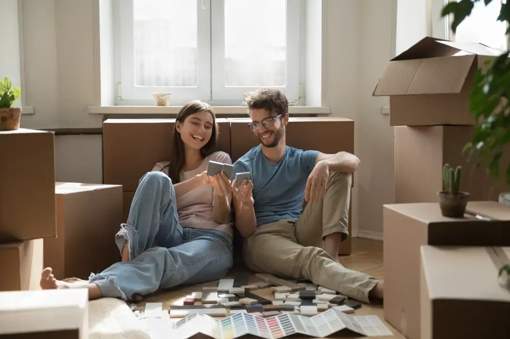 Home made together. Joyful excited young husband wife own flat apartment buyers sit on floor at relocation day plan improvement renovation review tile swatches color guides share interior design ideas