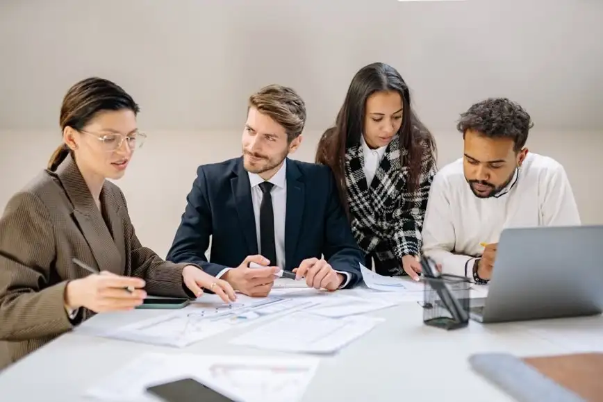 A group of people looking over papers at a conference table.