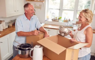 Senior Couple Downsizing In Retirement Packing And Labelling Boxes Ready For Move Into New Home
